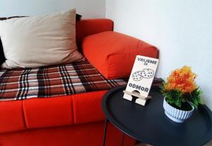 a red couch with a table with a sign on it at Apartman Nino in Tounj