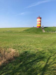 a lighthouse sitting on top of a grass field at Ferienhaus Pilsum in Krummhörn