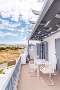 een balkon met witte meubels en een tafel en stoelen bij IKIES TINOS A and B in Tinos Town