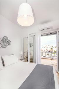 a white bedroom with a bed and a large window at IKIES TINOS A and B in Tinos Town