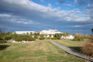 a house with a grassy yard with a driveway at Old Bones Lodge in Oamaru