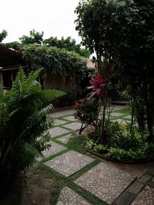 een tuin met een stenen loopbrug met bomen en planten bij Pousada do farol in Jericoacoara