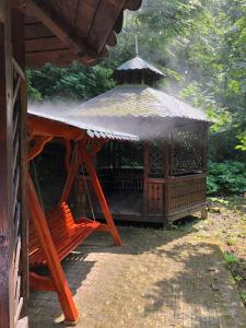 a wooden gazebo with a roof and a bench at Vila De Argint in Sinaia