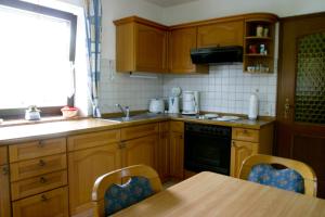Una cocina con gabinetes de madera y una mesa con sillas. en Gästehaus Steiger, en Bad Birnbach