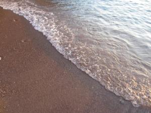 a close up of the sand and water on the beach at Kiknos Studios in Kalamaki