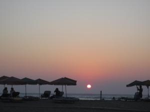 people sitting on the beach watching the sunset at Kiknos Studios in Kalamaki