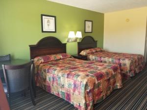 a hotel room with two beds and green walls at Oak Tree Inn Eupora in Eupora