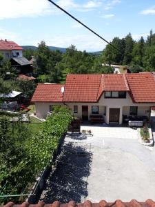 une maison avec un toit rouge et une allée dans l'établissement Apartments and Rooms Štefanac, à Slunj