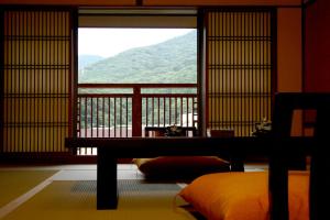 a room with a bed and a window with a view at Hakone Onsen Ryokan Yaeikan in Hakone