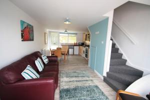 a living room with a couch and a staircase at Freshwater Bay Holiday Cottages in Pembroke