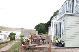 a porch with a picnic table on the side of a building at Freshwater Bay Holiday Cottages in Pembroke
