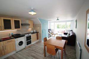 a kitchen and a living room with a table at Freshwater Bay Holiday Cottages in Pembroke