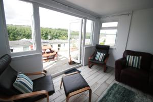 a living room with two chairs and a large window at Freshwater Bay Holiday Cottages in Pembroke
