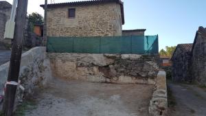 una pared de piedra junto a un edificio con una valla en CASA Eiró, en Lobios