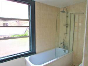 a bathroom with a shower and a bath tub with a window at Home away from home in London