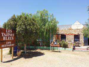 una señal frente a un edificio con un árbol en Les Tajines Bleus en Tamanar