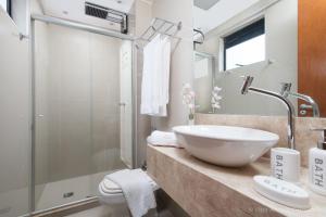a bathroom with a white sink and a shower at Apto 2Q com varanda no Ed Maximum Home in Natal