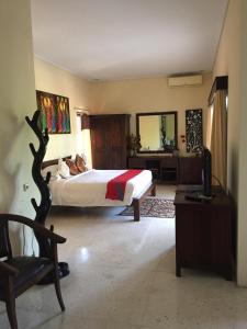 a bedroom with a bed and a desk and a television at Intan Mutiara Sanur Beach Villa in Sanur