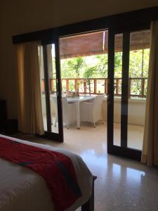 a bedroom with a bed and a balcony with a table at Intan Mutiara Sanur Beach Villa in Sanur