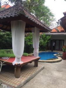 a patio with a umbrella next to a swimming pool at Intan Mutiara Sanur Beach Villa in Sanur