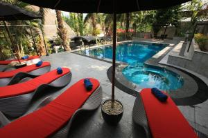 a swimming pool with red lounge chairs and an umbrella at Baan Heaven / Patong Beach Pool Villa Sleeps up to 15 in Patong Beach