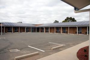 an empty parking lot in front of a building with solar panels at Highway Inn Motel in Hay