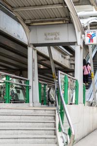 Una mujer subiendo las escaleras de una estación de metro en Udomsuk Inn & Cafe Since 2019 - BTS Udomsuk, en Bangkok