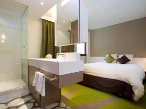 uma casa de banho com uma cama, um lavatório e um espelho. em ibis Styles Bordeaux Aéroport em Mérignac