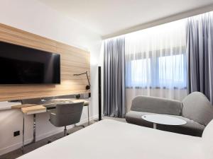 トゥールにあるノボテル トゥール サントル ガールのベッド、デスク、テレビが備わるホテルルームです。
