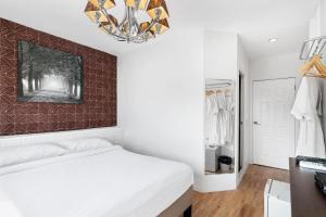 a bedroom with a white bed and a red accent wall at Udomsuk Inn & Cafe - BTS Udomsuk in Bangkok