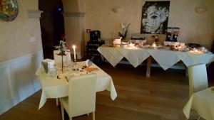 2 mesas en una habitación con manteles blancos y velas en B&B Villa Fiorini, en Moniga del Garda
