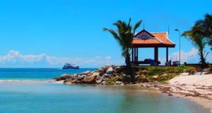 a building on the beach with a boat in the water at Tea Moon Beach House in Thongsala