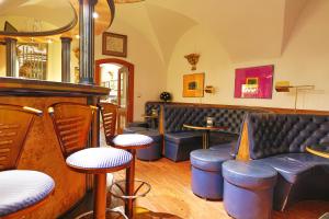 a bar with chairs and a couch and tables at Royal Ricc in Brno