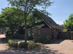 une maison en briques avec un arbre devant elle dans l'établissement 't Hulzen 55 or 61 Winterswijk, à Winterswijk