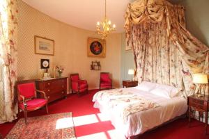 - une chambre avec un lit et deux chaises rouges dans l'établissement Domaine de Bort, à Saint-Priest-Taurion