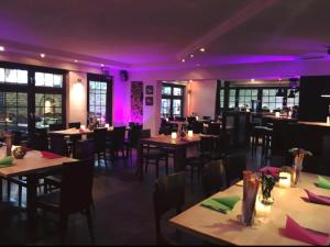 a restaurant with tables and chairs and purple lighting at Köhlz Fewo & Restaurant im EG in Bornheim