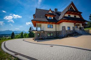 a house with a gambrel roof on a driveway at Willa Góralskie Klimaty in Bukowina Tatrzańska