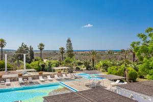 a view of the pool at a resort with palm trees at Tenuta Terenzano in Torre San Giovanni Ugento