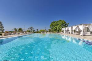 a large swimming pool with blue water and chairs at Tenuta Terenzano in Torre San Giovanni Ugento