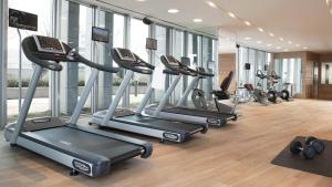 a gym with a row of treadmills and elliptical machines at LOTTE City Hotel Jeju in Jeju