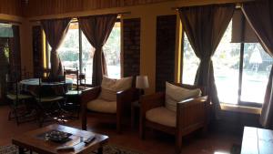ein Wohnzimmer mit Stühlen, einem Tisch und Fenstern in der Unterkunft Cabaña Campestre de 1 Ambiente En Paine in Paine