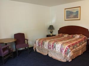een slaapkamer met een bed, een tafel en een stoel bij New Kansan Motel in Rancho Cucamonga