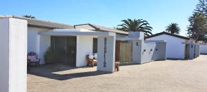 a small white house with a table and a chair at Tiende Laan Bed & Breakfast and Self-Catering in Walvis Bay