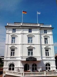諾德奈的住宿－Hotel Künstlerhaus，上面有两面旗帜的白色建筑