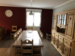 a dining room with a table and chairs and a clock at LE CANT DE JUME in Gérardmer