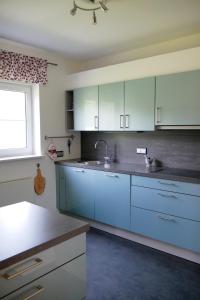 cocina con armarios azules, fregadero y ventana en Ferienhaus/Ferienwohnung BeeHappy en Aichstetten