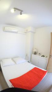 1 dormitorio con cama blanca y manta roja en Front de mer T2 PALAVAS LES FLOTS direct plage, en Palavas-les-Flots