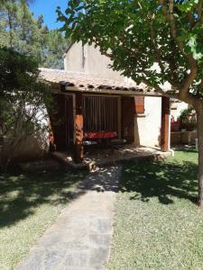 a small house with a porch and a tree at Camping Mozziconaccio in Sainte-Lucie de Porto-Vecchio