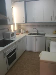 a kitchen with white cabinets and a sink and a microwave at Torrox costa apartamento in Torrox Costa