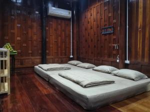 two beds in a room with wooden walls at Bansuwan Homestay in Amphawa